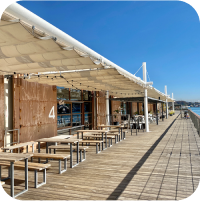 海沿いのテラス席、たくさんの木製のテーブルと椅子